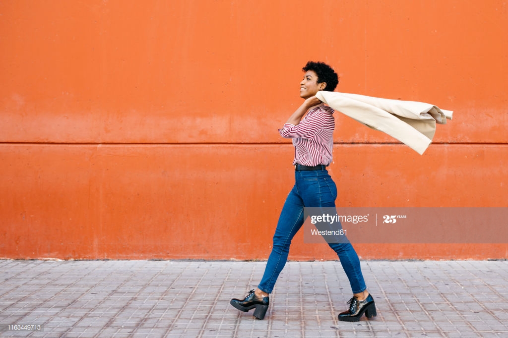 Businesswoman Walking At A Red Wall In The Background Putting Her