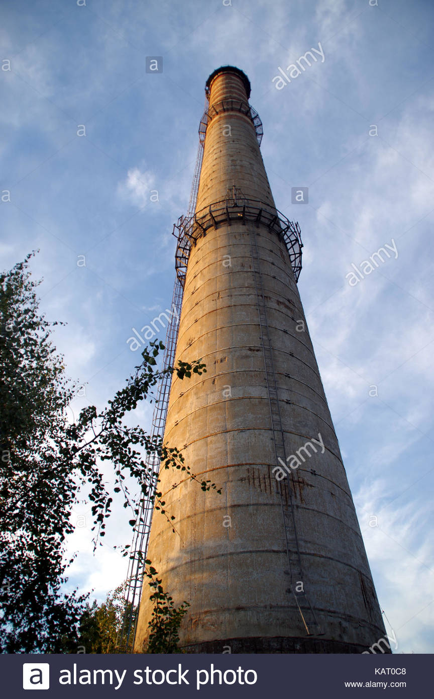 Old Concrete High Chimney On Cloudy Sky Background Stock Photo