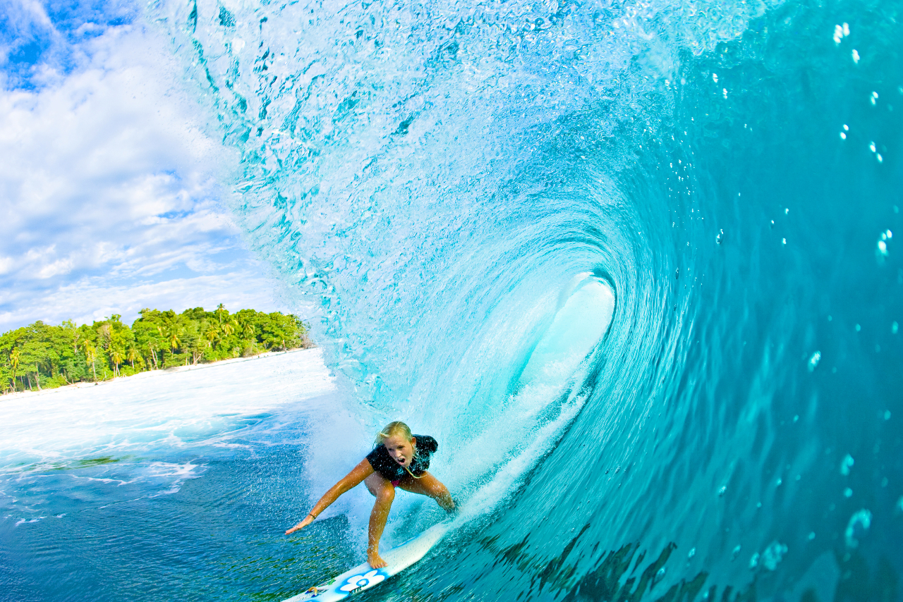 A surfer riding a beautiful turquoise wave in a tropical paradise