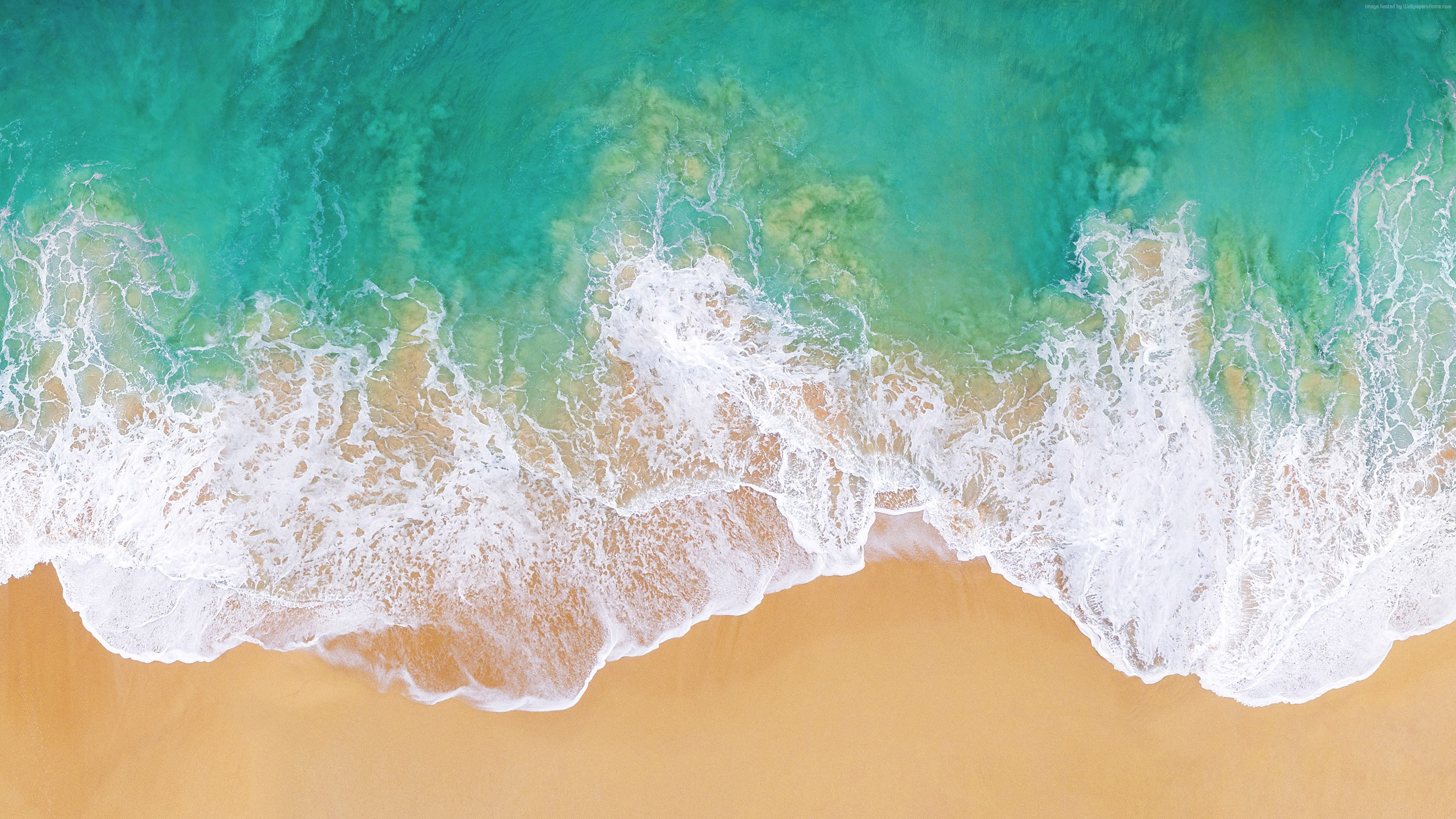 Aerial view of turquoise ocean waves crashing on a sandy beach