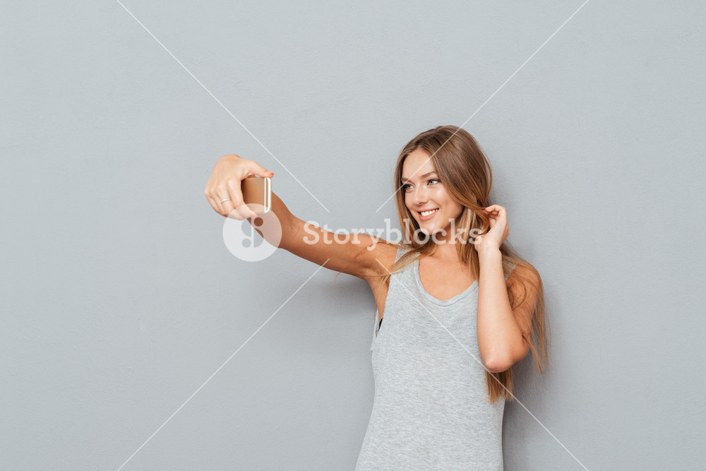 Smiling Young Girl Making Selfie Photo On Smartphone Over Gray