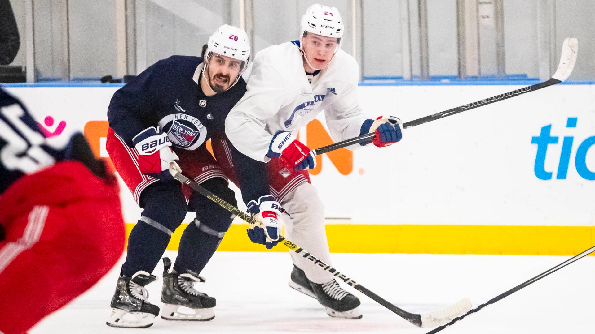 Two New York Rangers hockey players compete for the puck during a game