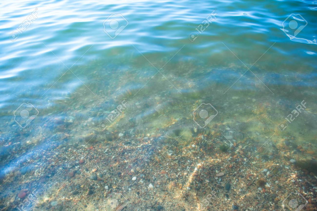 Seabed From Small Pebbles Through Clear Water Background Stock