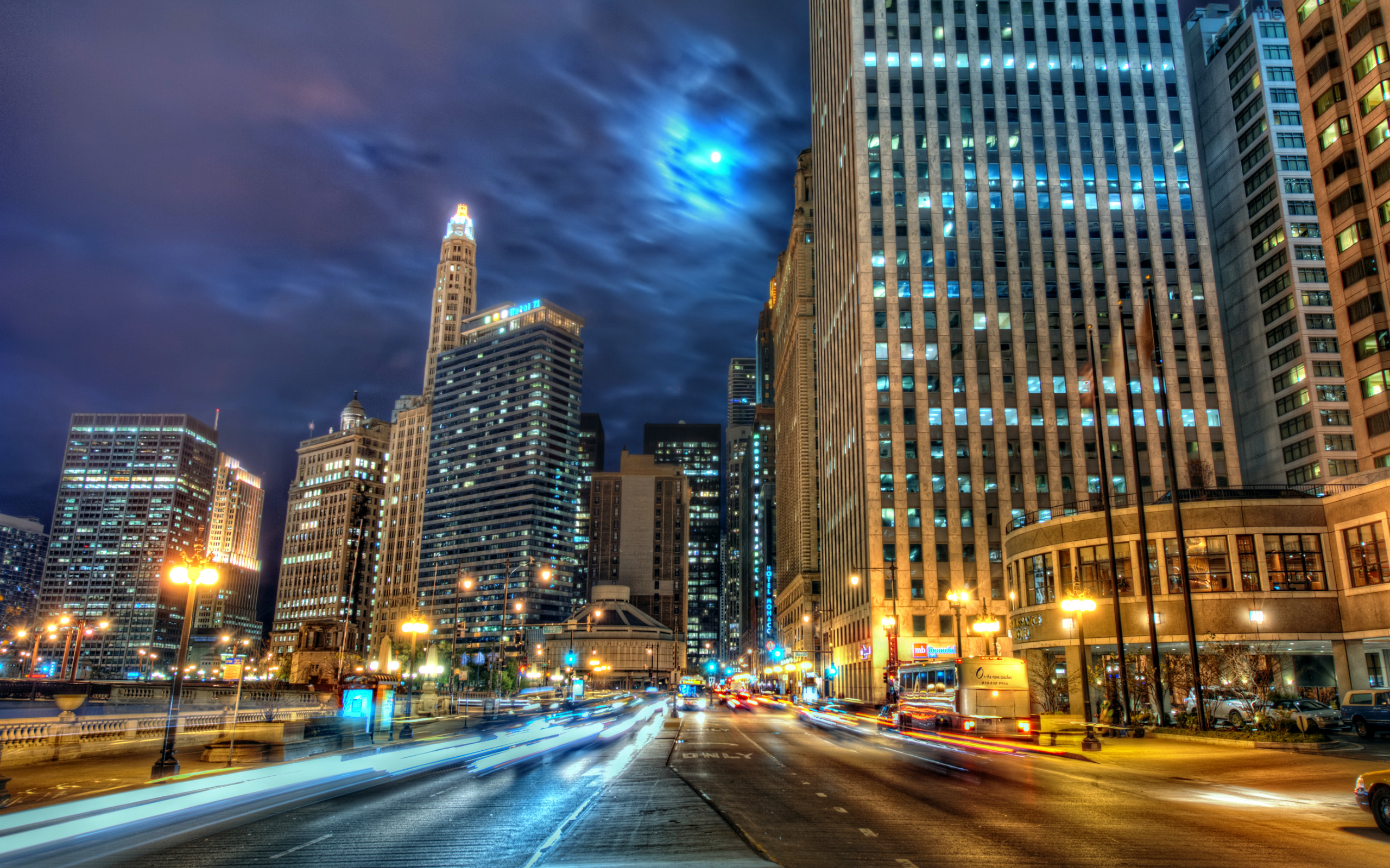 Chicago skyline at night with illuminated skyscrapers, traffic trails, and a full moon