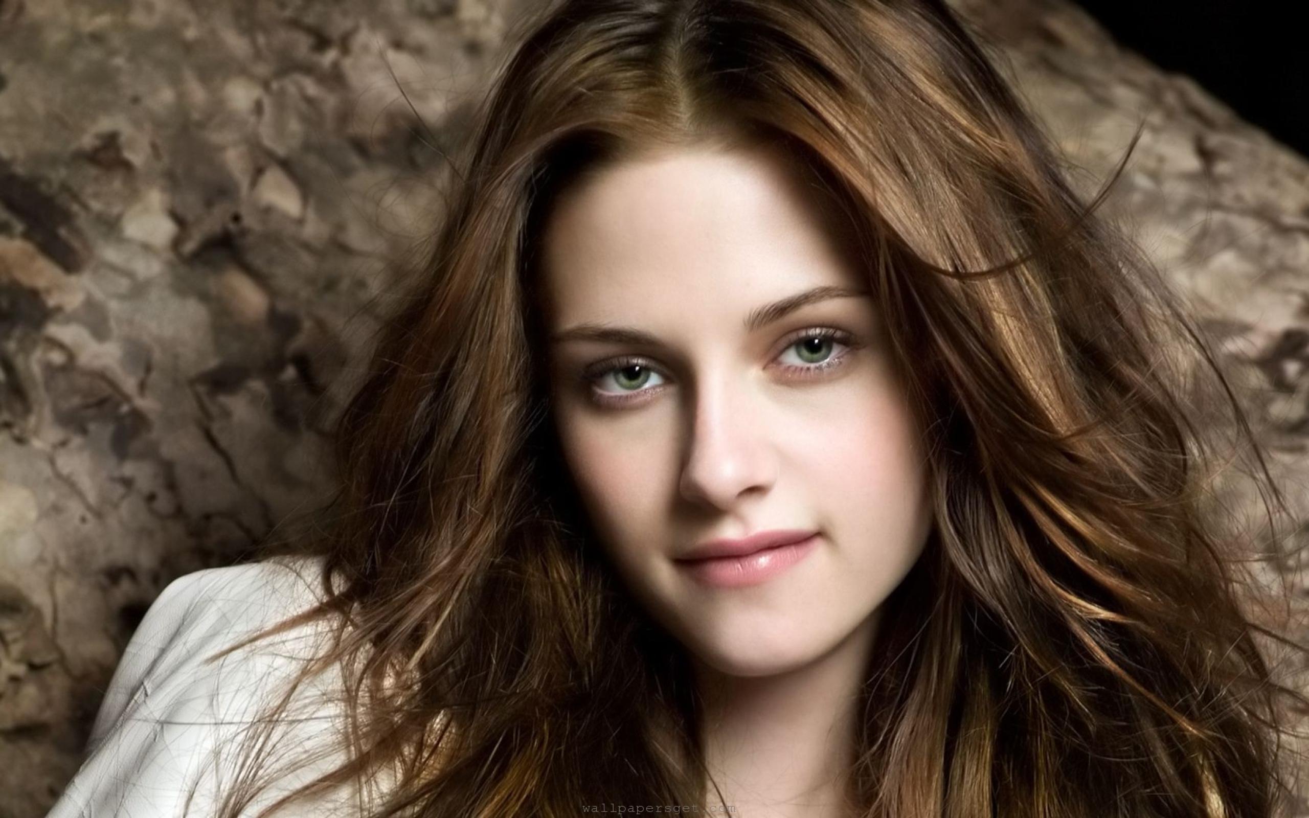 Close-up portrait of a young woman with long brown hair, giving a soft smile