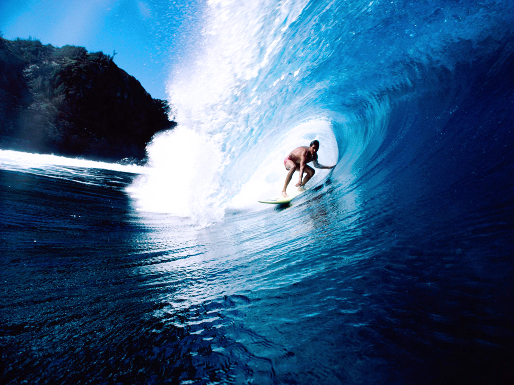 A surfer rides a powerful wave in a tropical ocean, showcasing the thrill and beauty of surfing