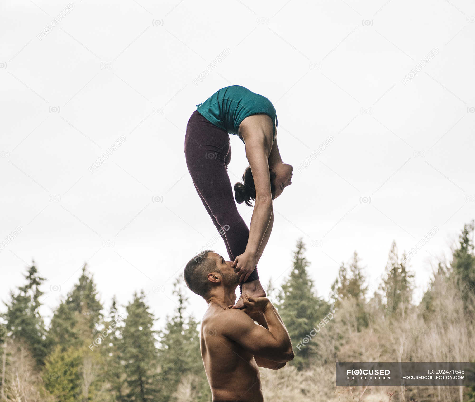 Couple Practicing Acroyoga With Forest At Background Full Frame