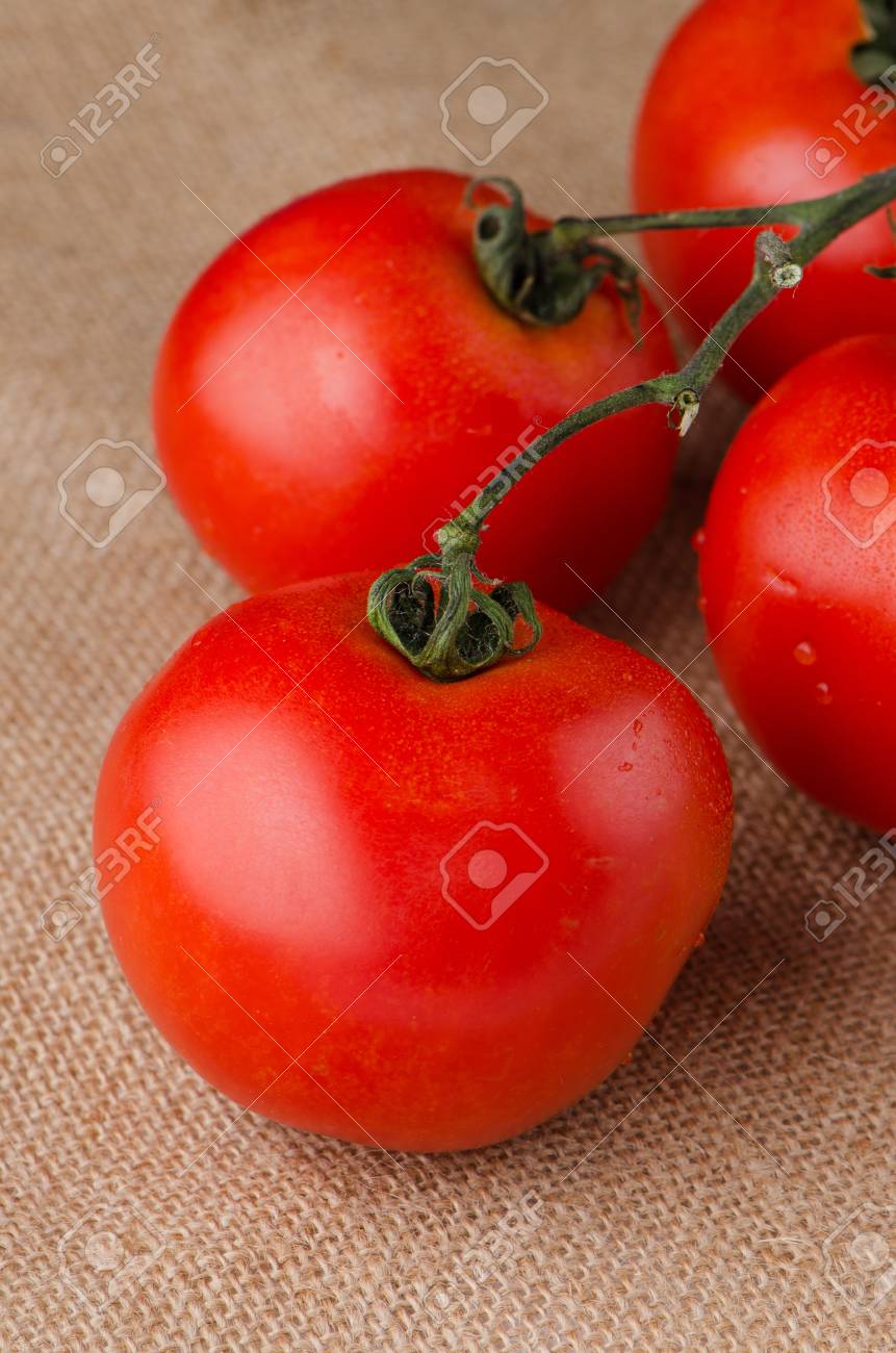Cherry Tomatoes On The Vine Over Raffia Background Stock Photo