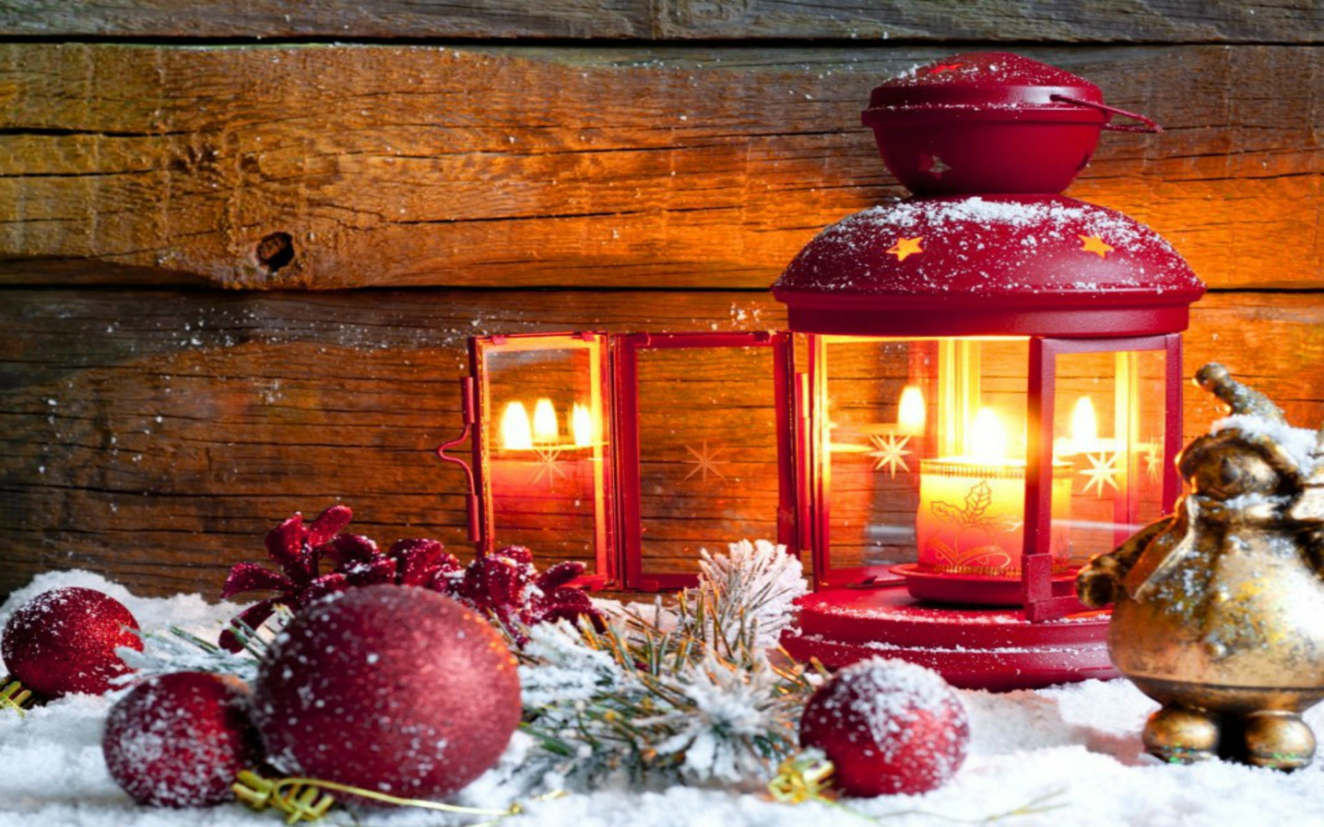 Christmas still life with red lantern, candles, ornaments, and snow on a rustic wooden background