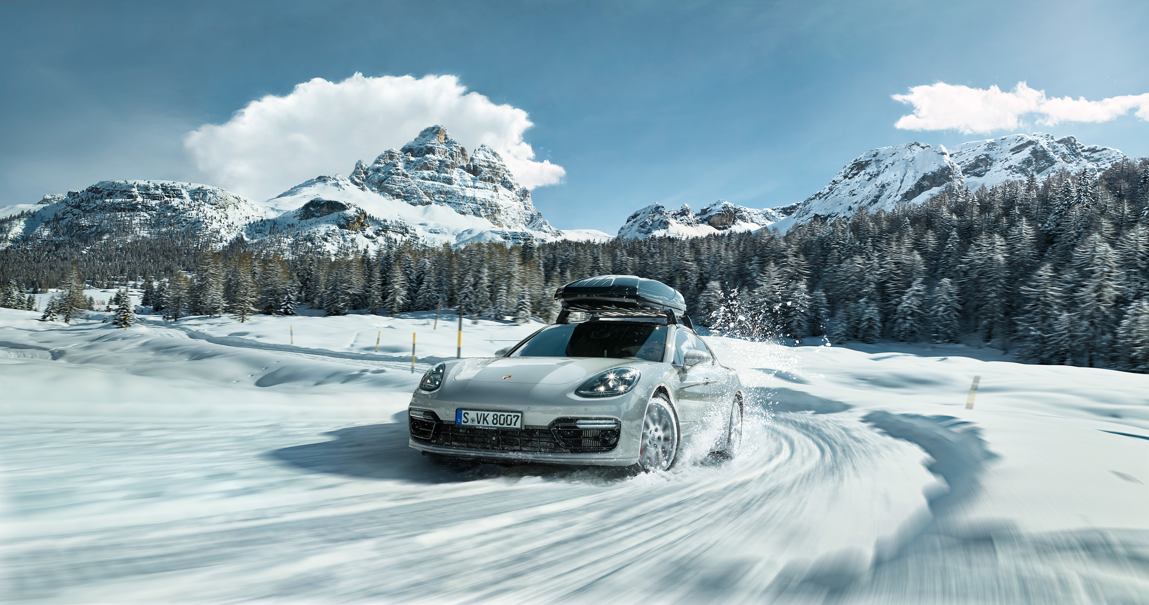 Silver Porsche Panamera driving on a snowy mountain road