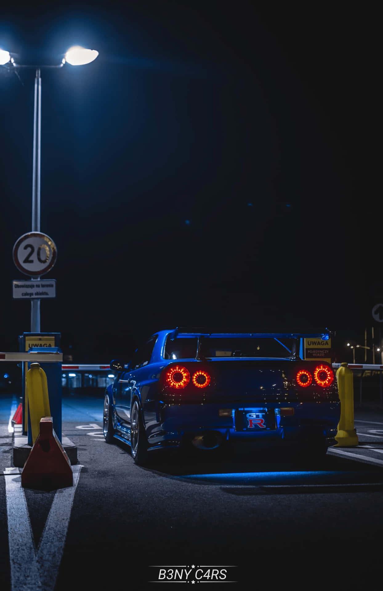 A Blue Sports Car Parked In Parking Lot At Night