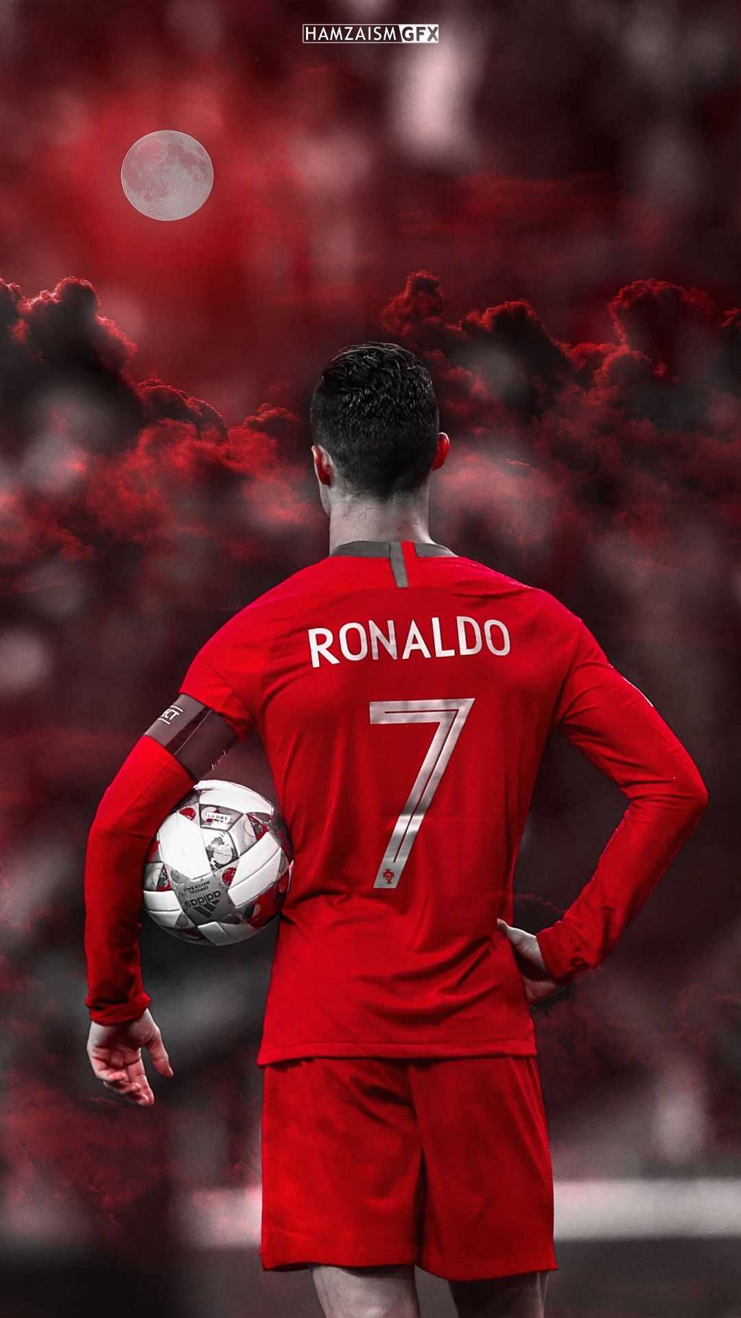 Cristiano Ronaldo, wearing his iconic number 7 jersey in Portugal's colors, stands with his back to the camera, holding a soccer ball. The backdrop features a dramatic red sky and a prominent moon, creating an awe-inspiring atmosphere