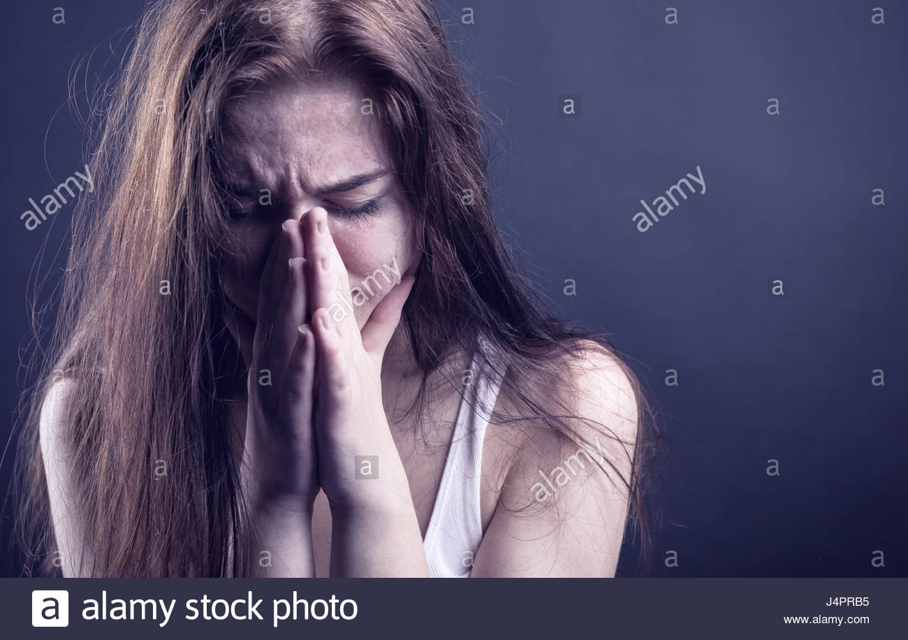 Young Woman Crying Face In Her Hands On A Dark Background Stock