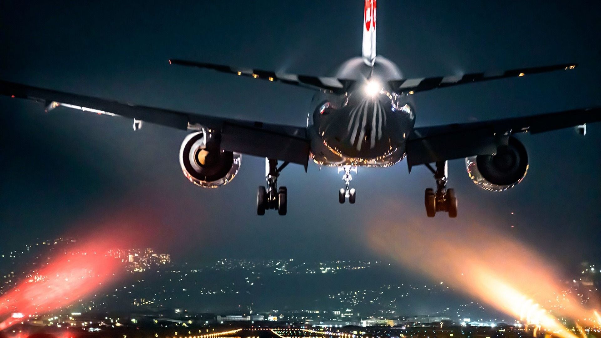 A passenger airplane descending for landing at night, with city lights twinkling in the background