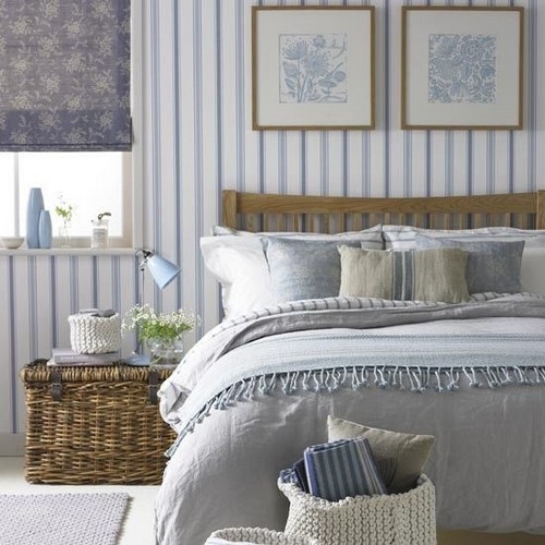 Blue and white striped wallpaper in bedroom with round gold mirror