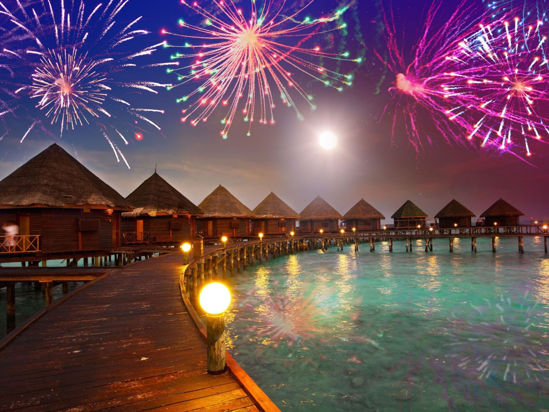 Fireworks light up the night sky over a row of idyllic overwater bungalows in the Maldives, creating a festive New Year's Eve scene
