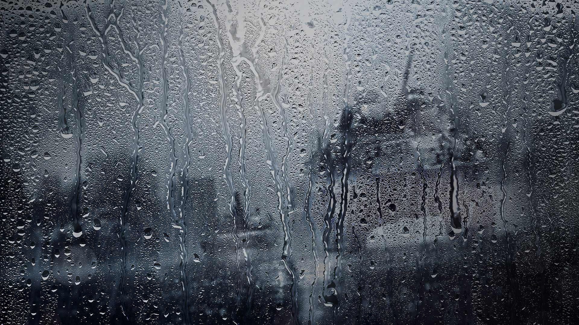Rain drops on a window pane, creating a blurry view of the outside world