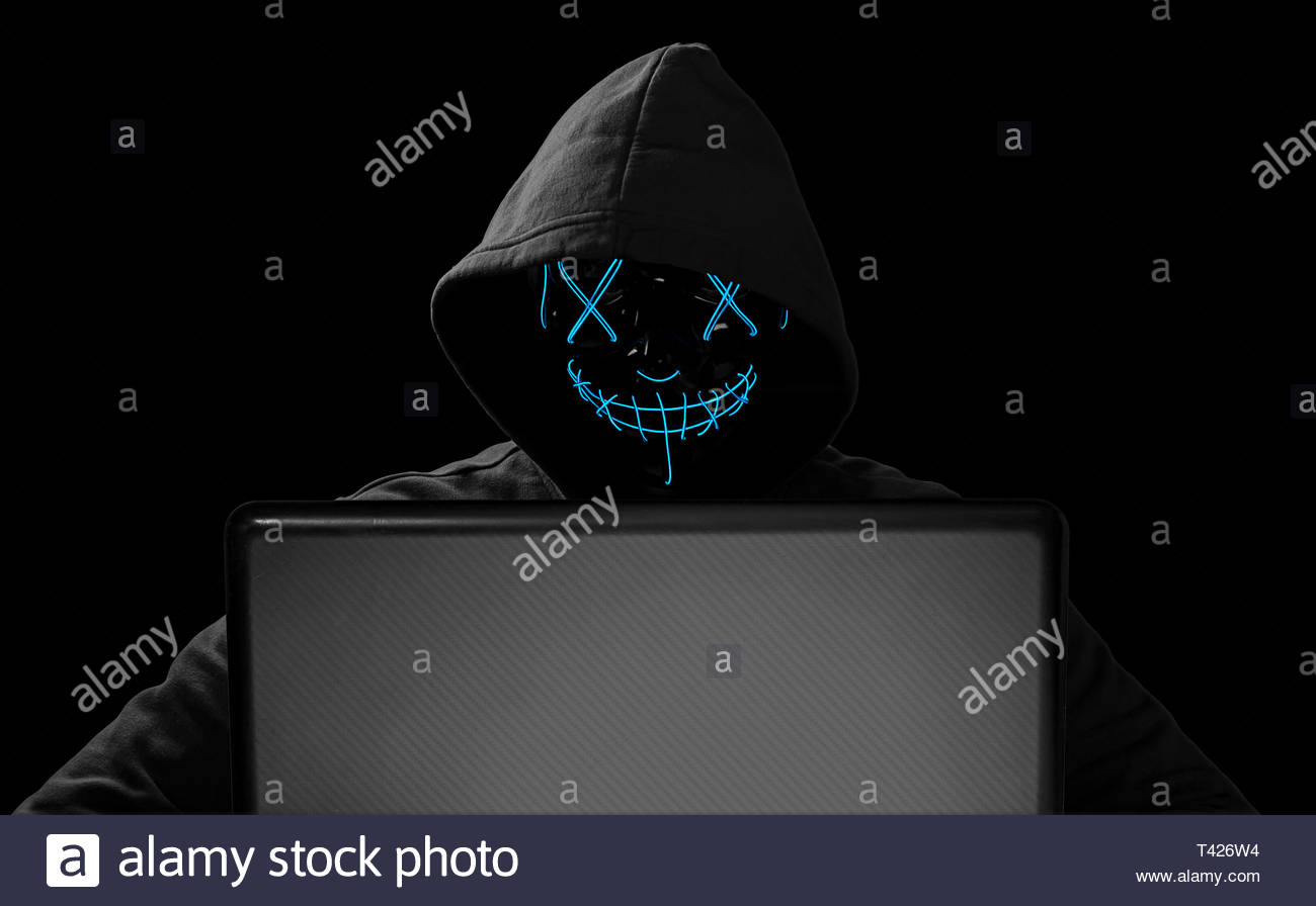 Hacker With Glowing Mask Behind Notebook Laptop In Front Of