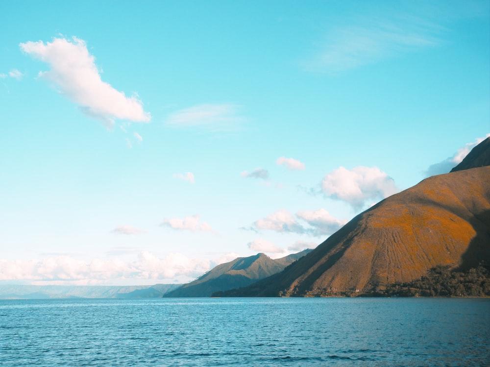 A Body Of Water With Mountains In The Background Photo Blue