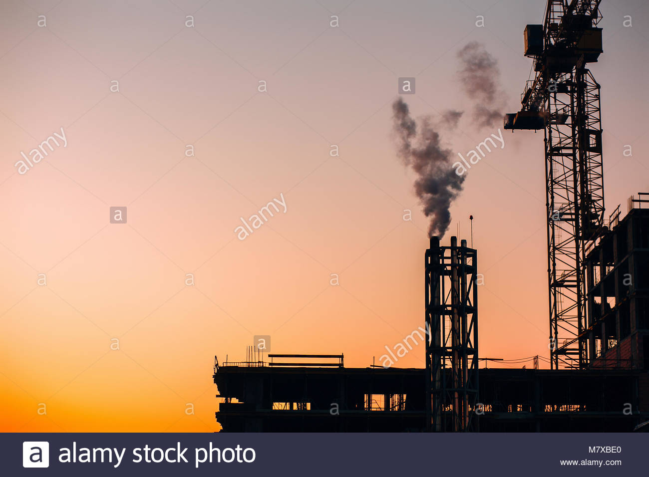 Crane And Building Construction Site With Pipe Smoke On Stock