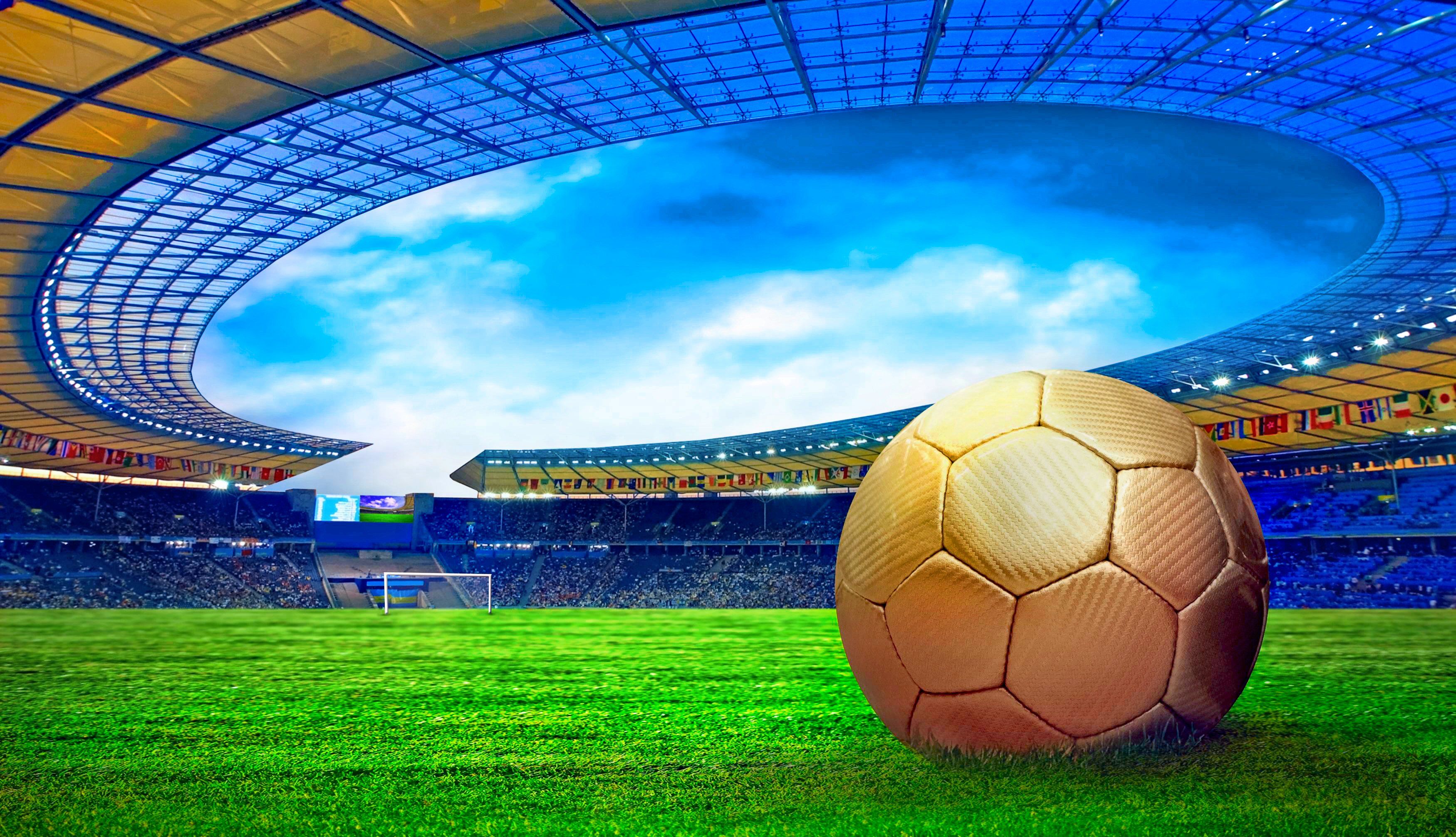 A golden soccer ball sits on a lush green field in a vibrant stadium, ready for a thrilling match. Flags of different nations adorn the stands, adding to the international feel