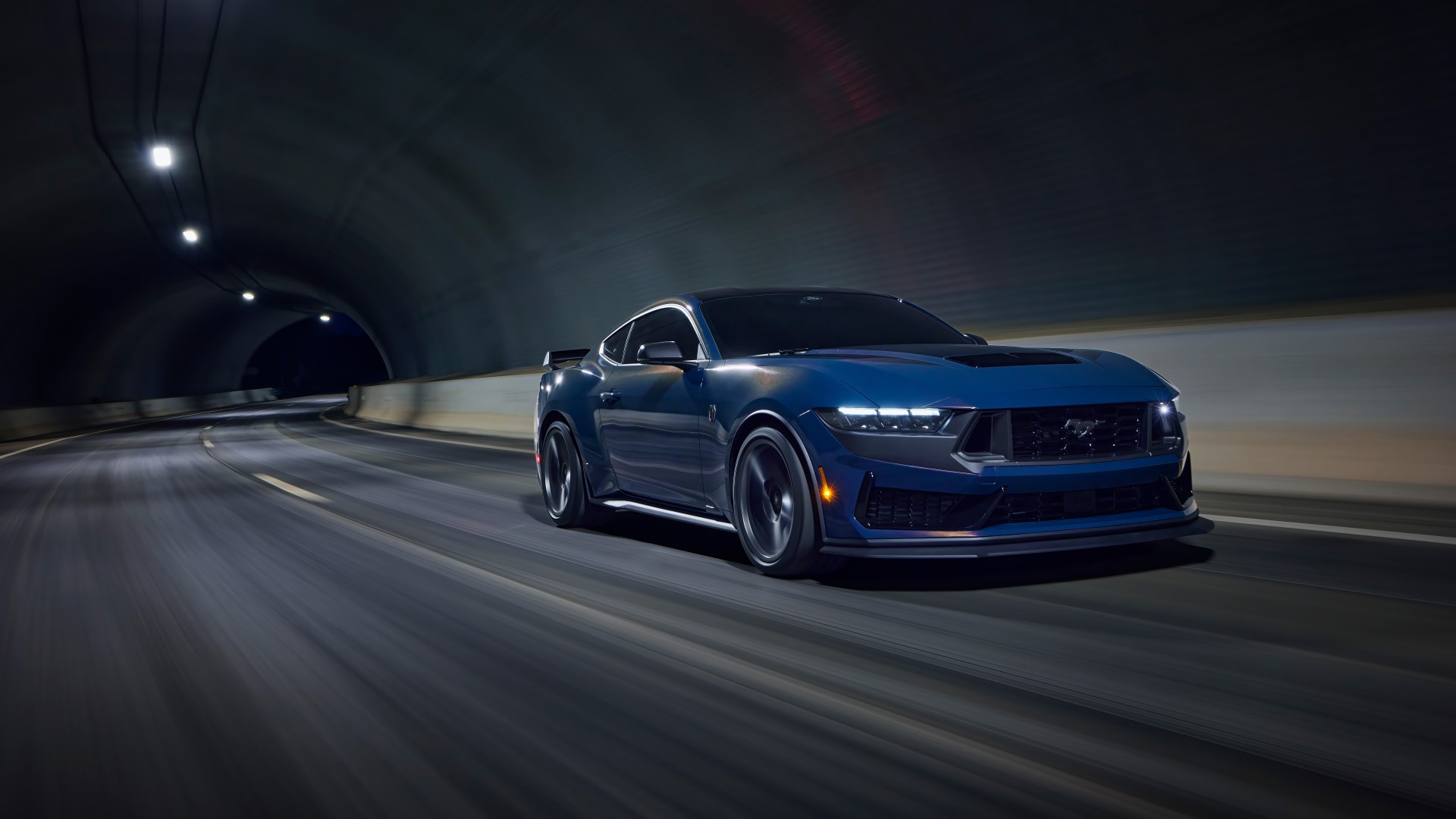 A dark blue Ford Mustang Dark Horse coupe speeding through a dimly lit tunnel, showcasing its sleek design and powerful performance