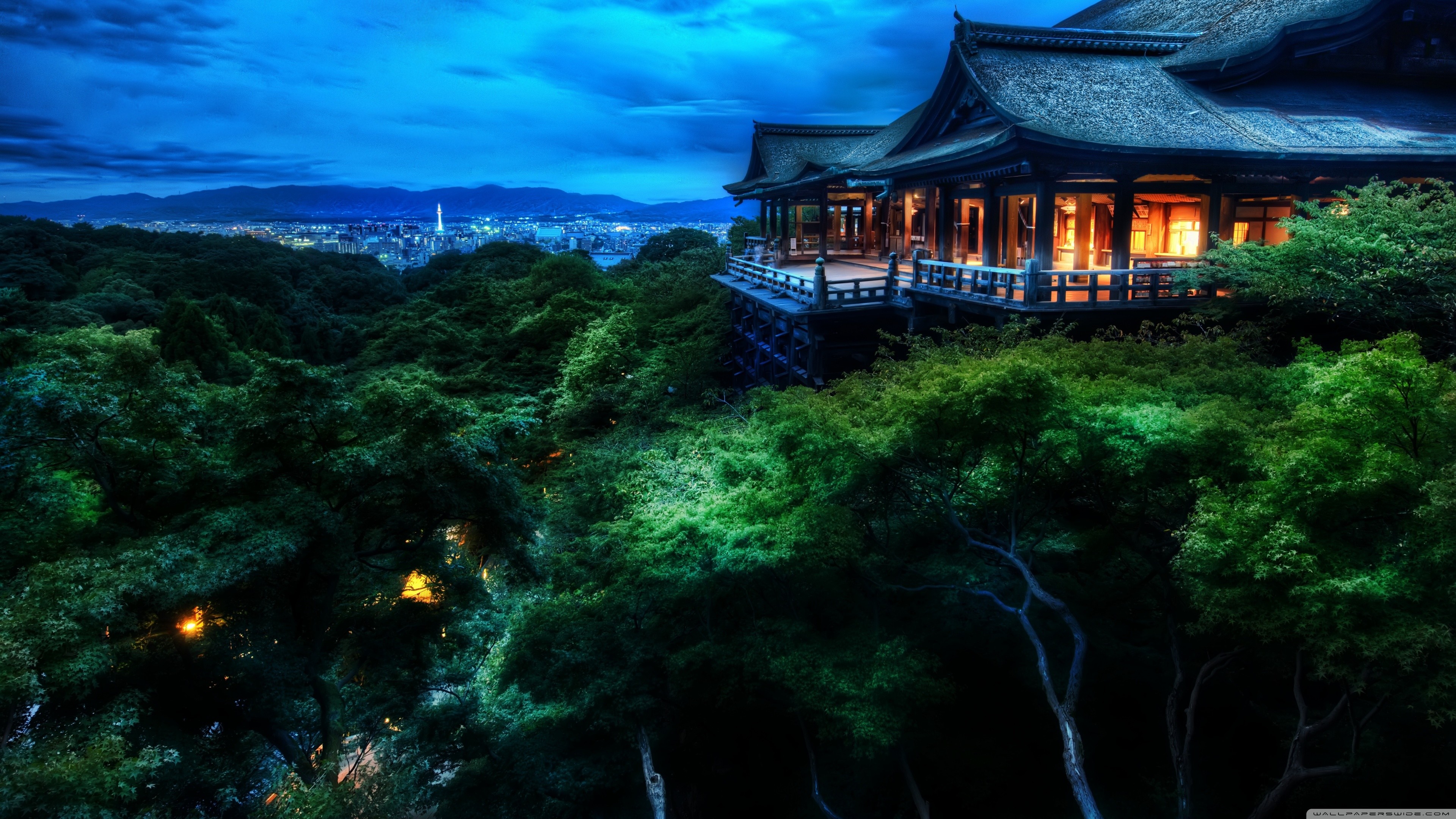 A traditional Japanese building overlooking a lush forest and a cityscape at dusk, evoking a sense of tranquility and beauty