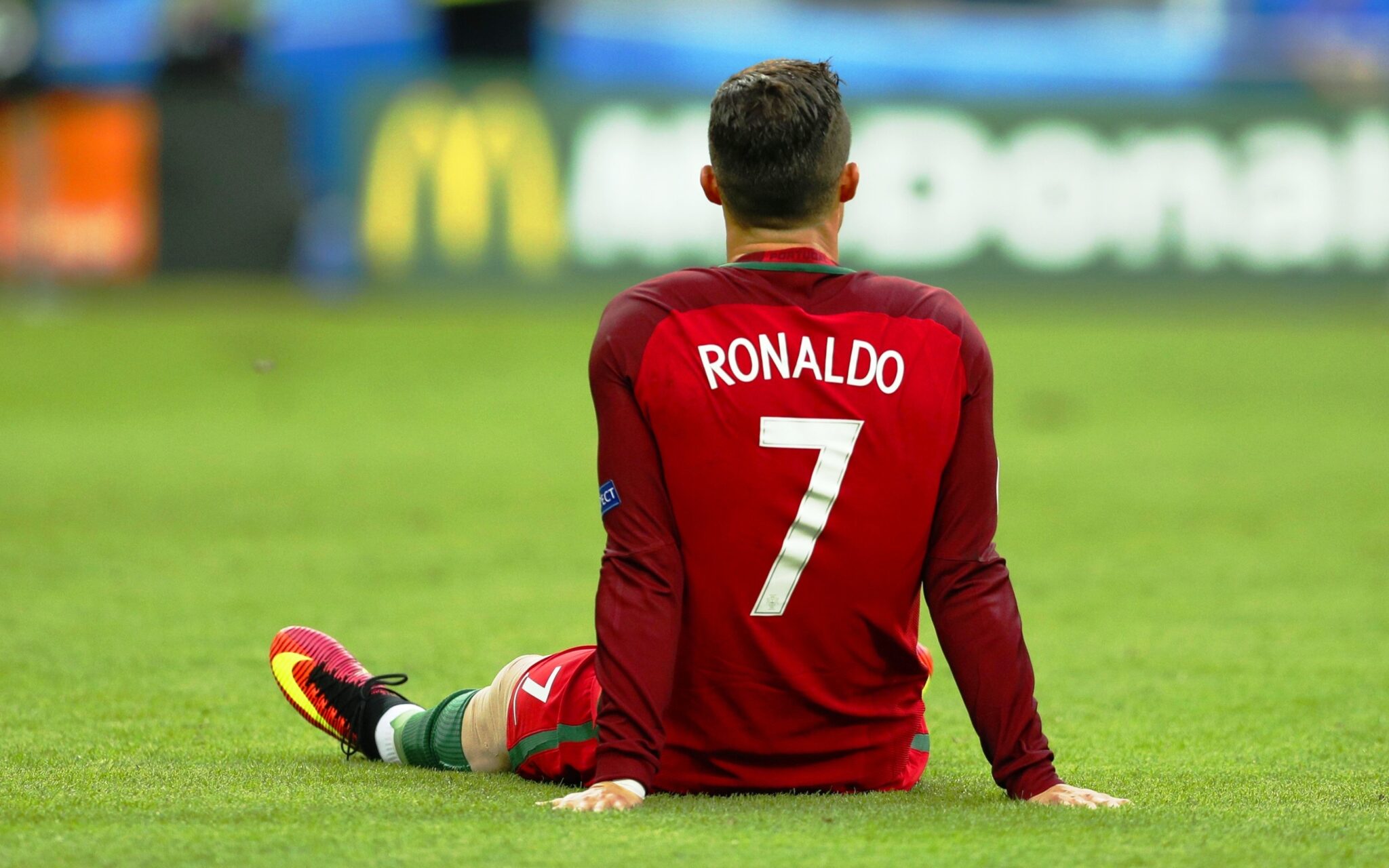 Cristiano Ronaldo sits dejected on the soccer field, wearing a Portugal jersey with his iconic number 7
