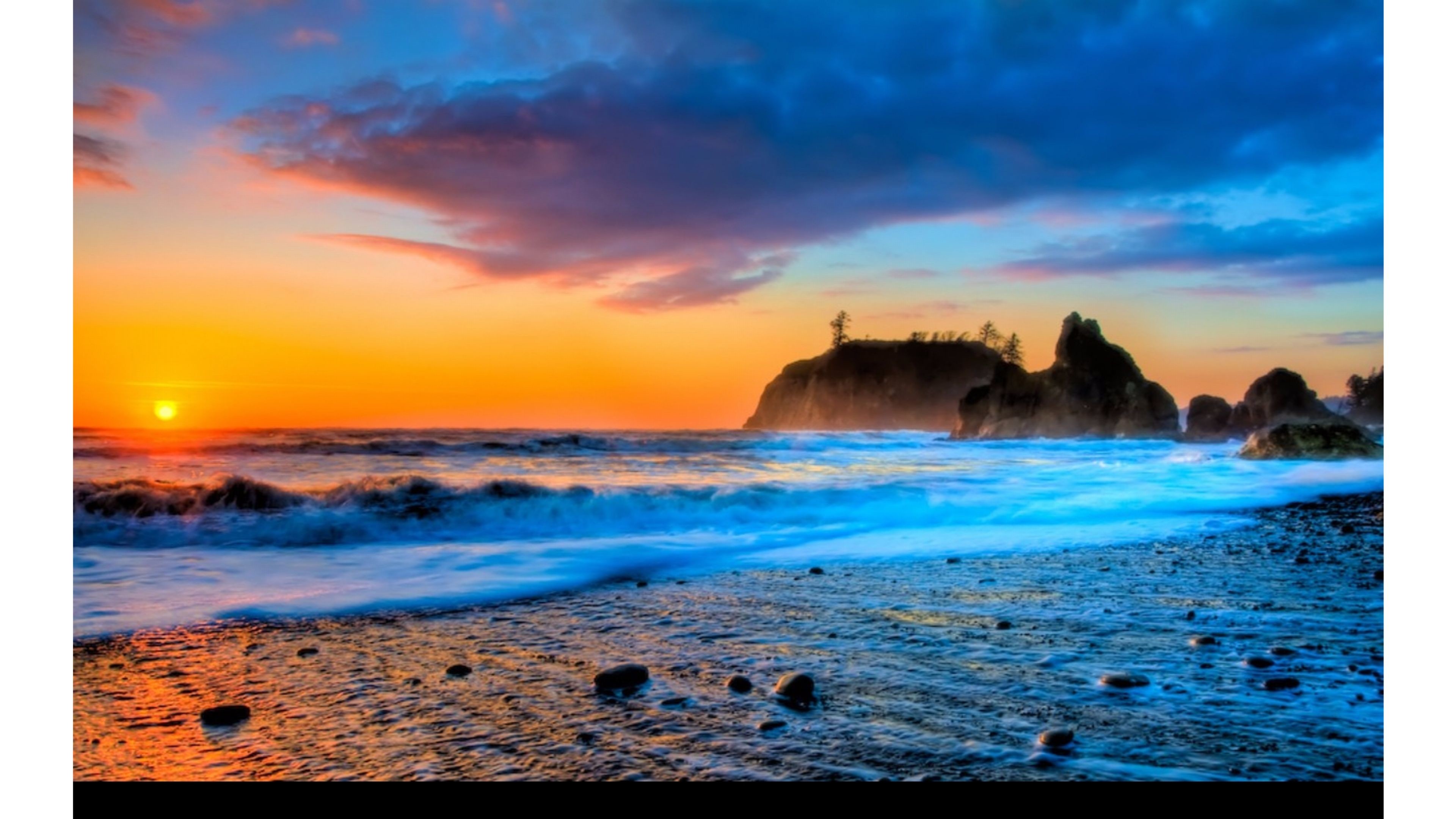 Vivid sunset over a rocky Pacific Northwest beach, with vibrant colors reflecting in the wet sand and waves
