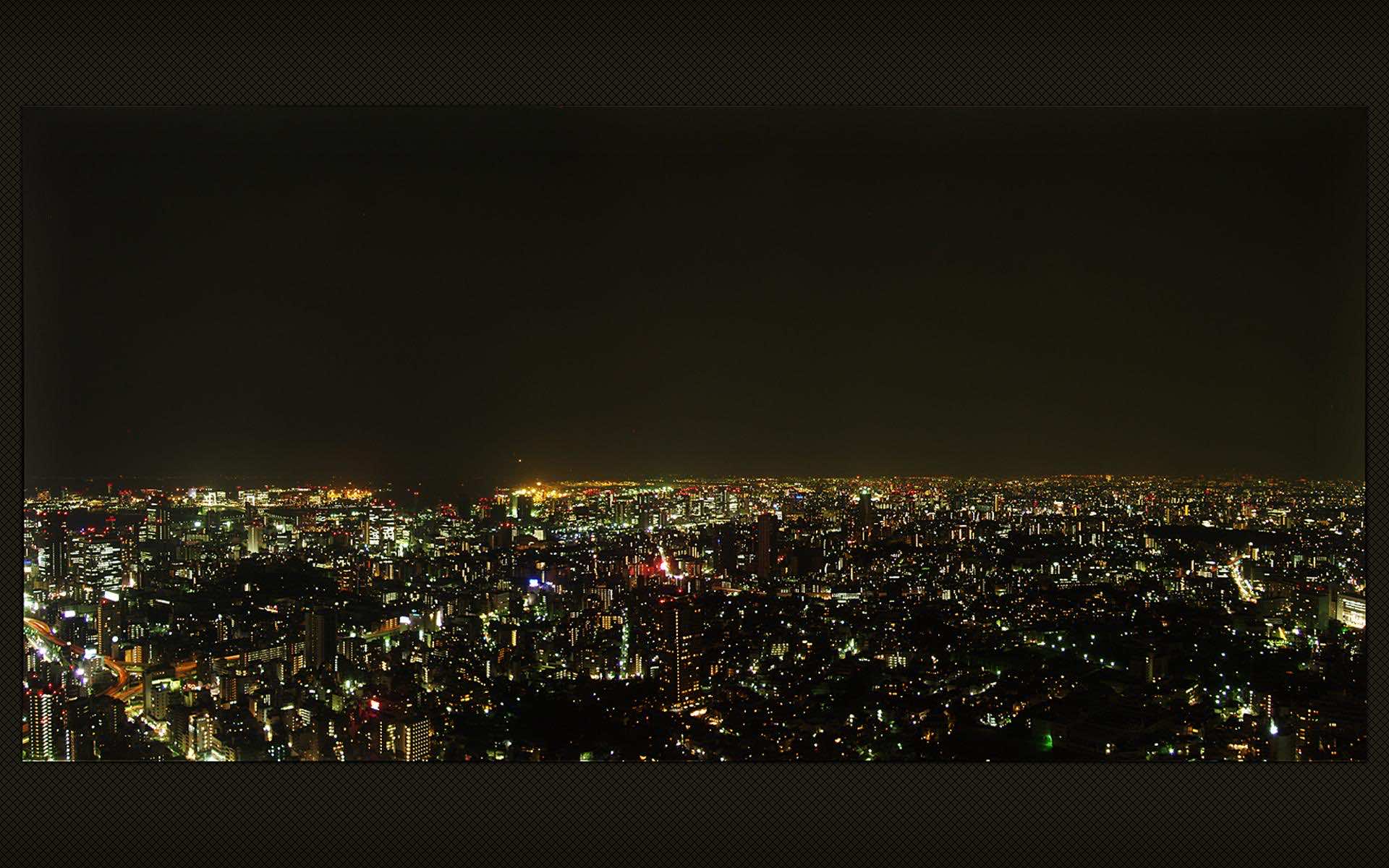 A breathtaking panoramic view of a sprawling cityscape at night, illuminated by countless city lights, perfect for a laptop wallpaper