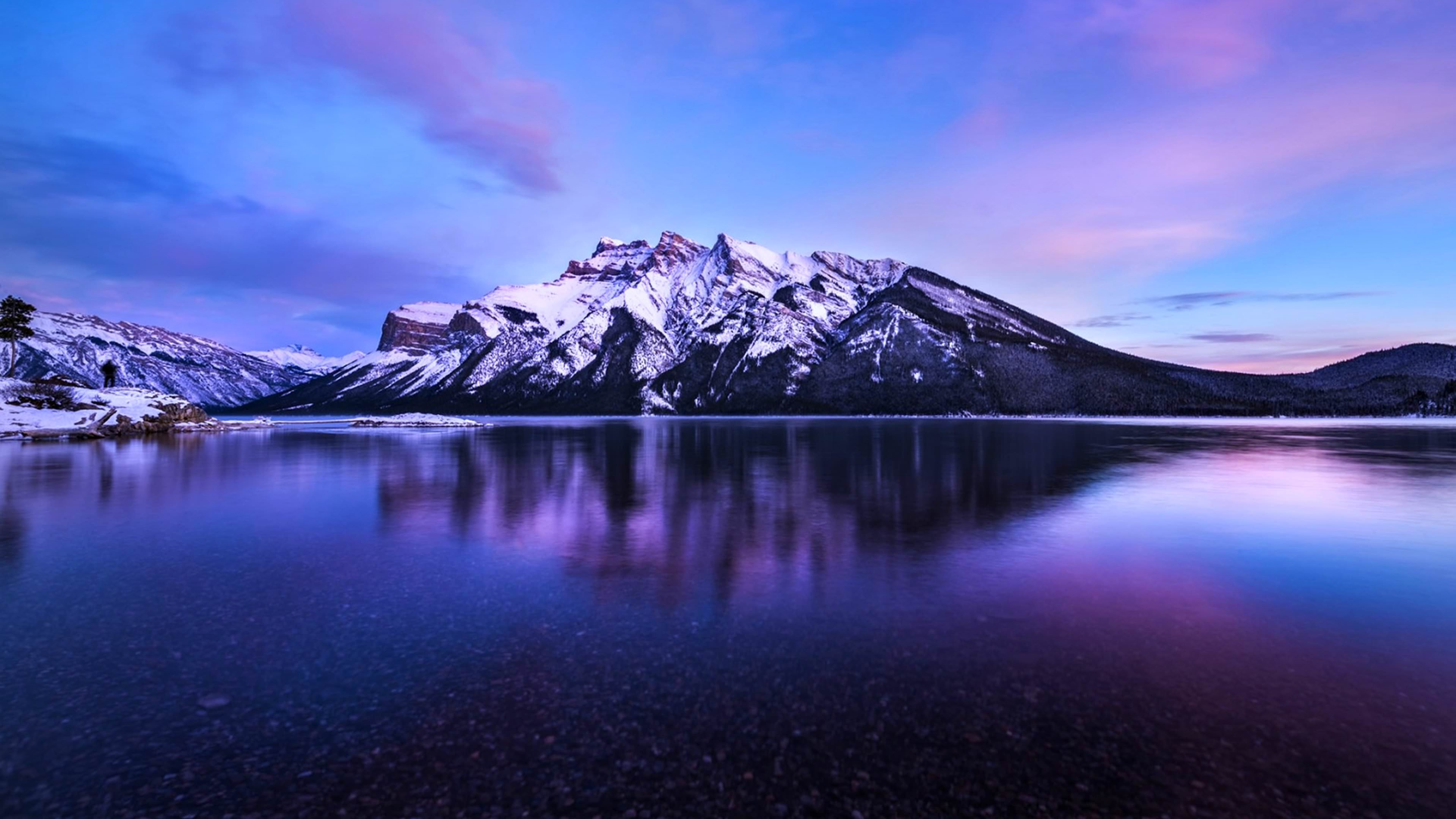 Stunning 4k background of a snow-capped mountain reflected in a serene lake at sunset
