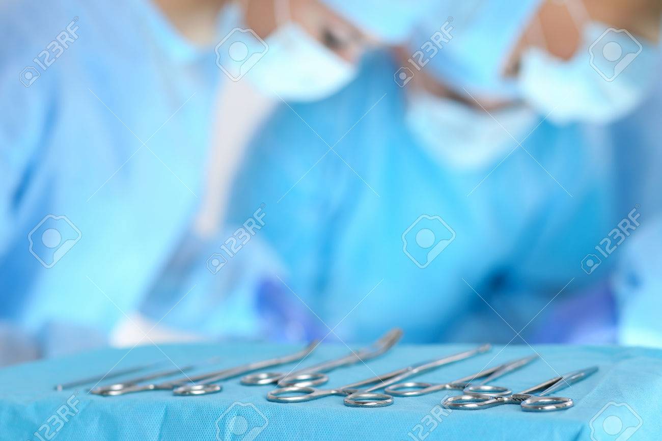 Surgical Tools Lying On Table While Group Of Surgeons At