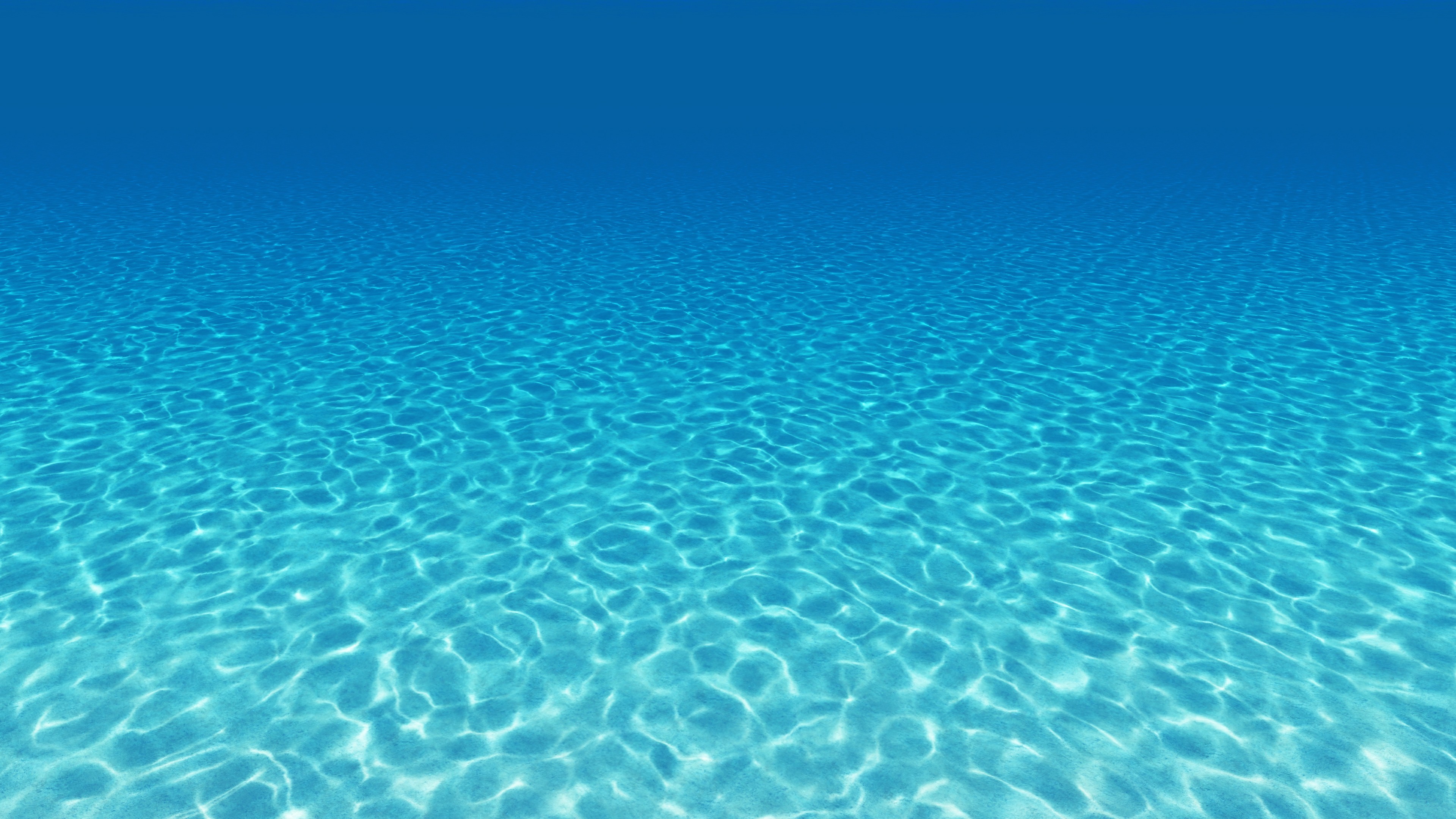 Tranquil turquoise underwater scene with rippling sunlight on the sandy seabed
