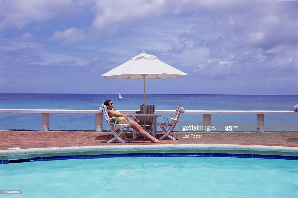 Young Woman Sunbathing By Pool Caribbean In Background Barbados