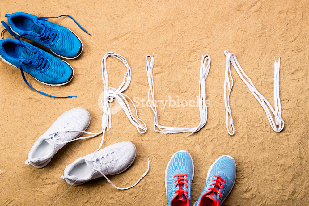 Blue Running Shoes And Run Sign Made Of Shoelaces Against Sand