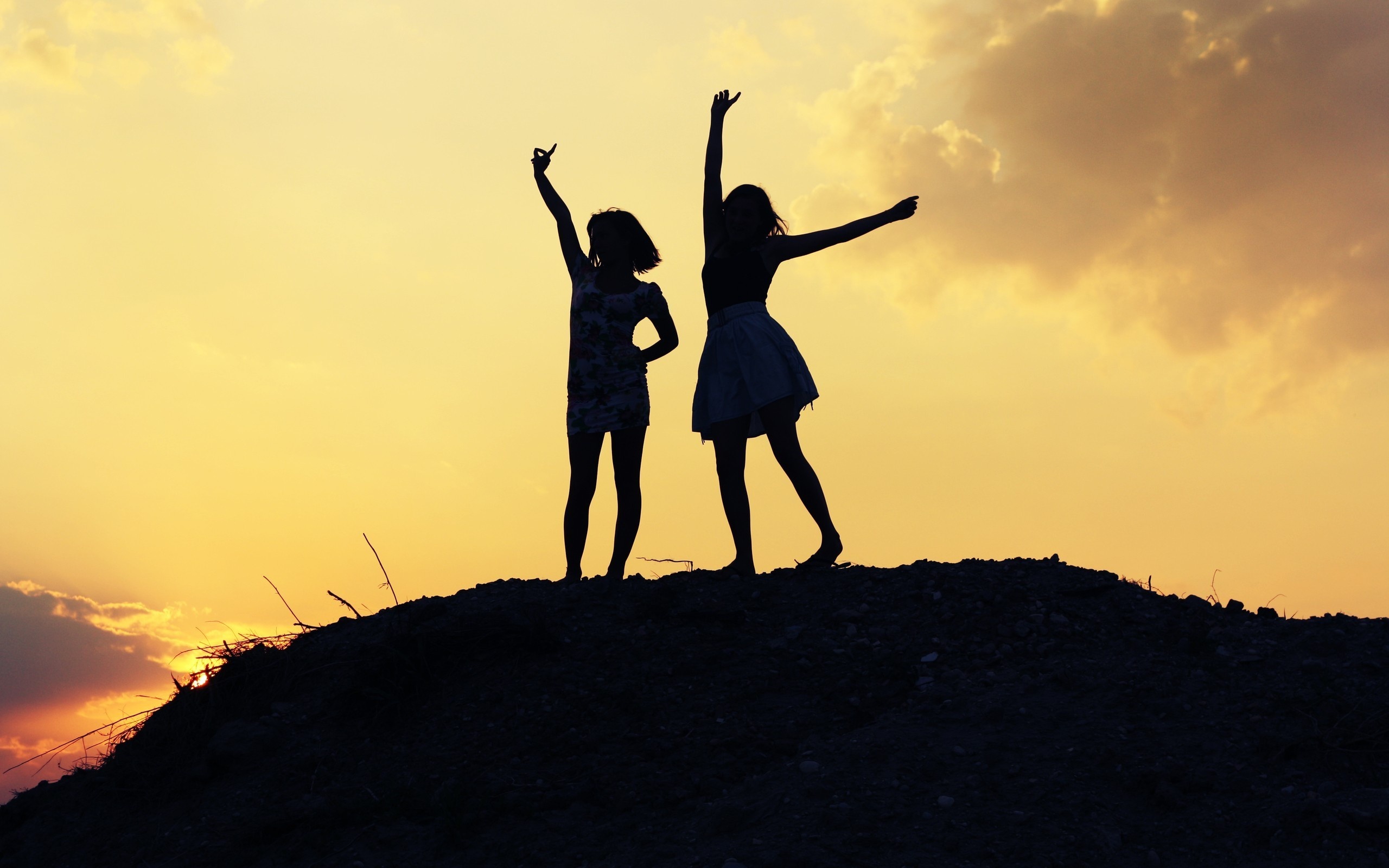 Silhouette of two friends celebrating friendship against a vibrant sunset backdrop