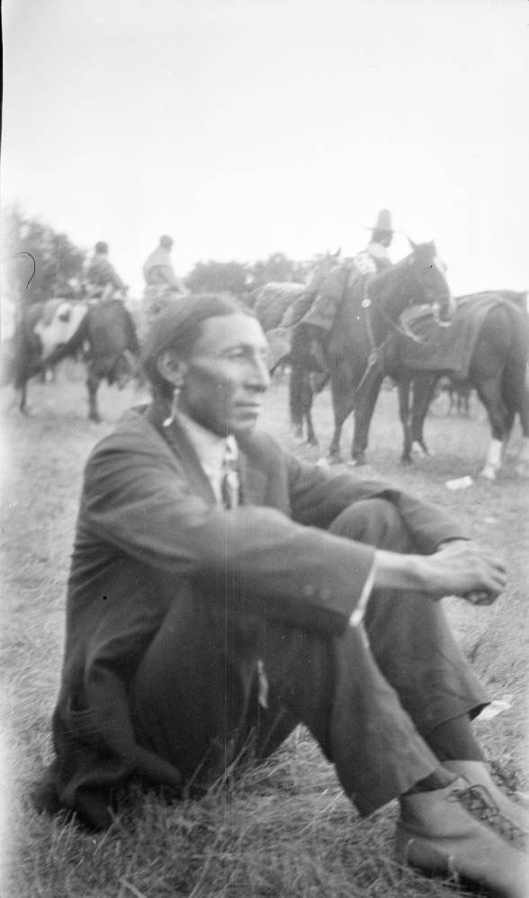 Cheyenne Man Sitting In Field Riders On Saddled Horses