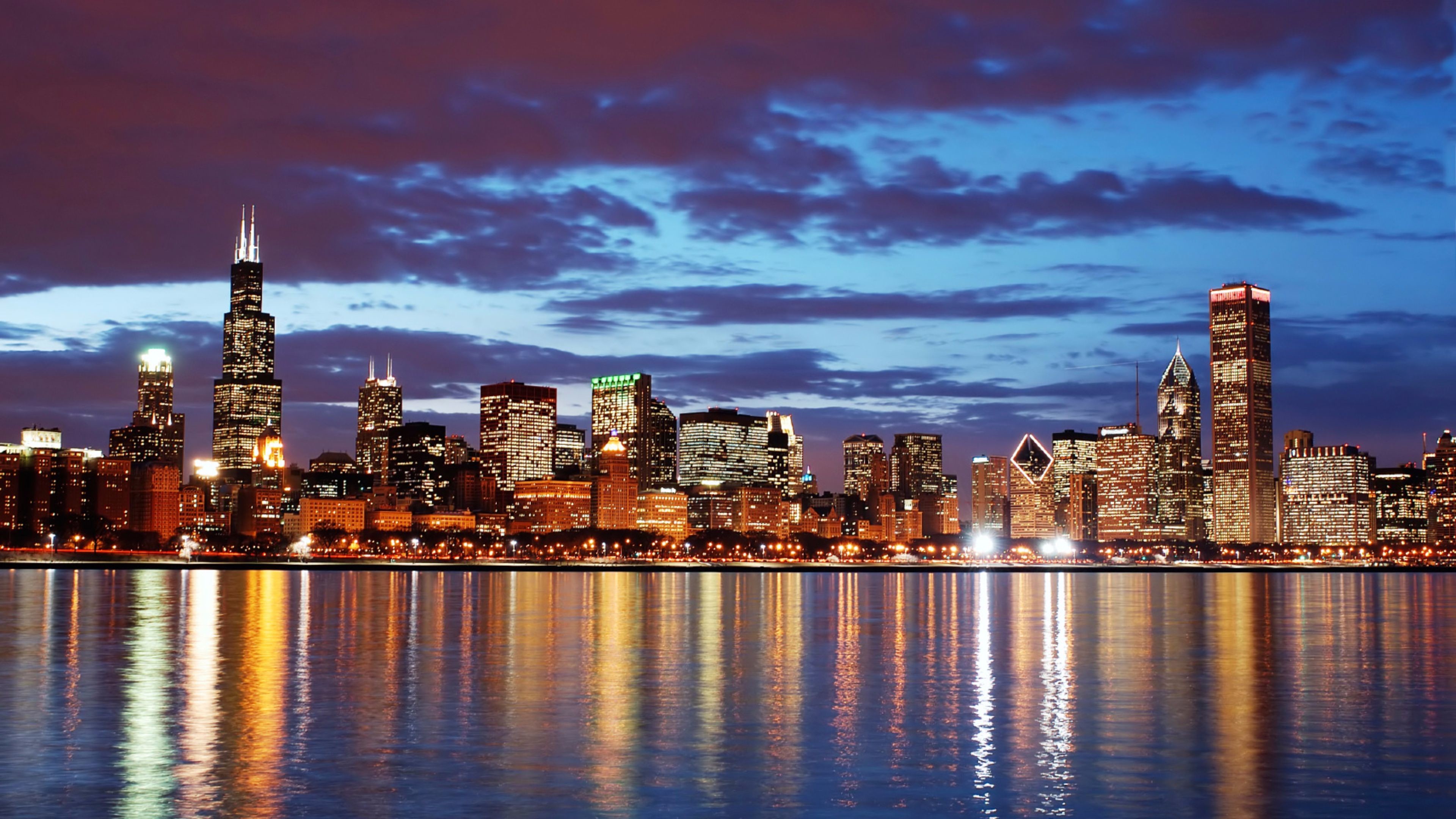 Chicago skyline at night with illuminated buildings reflected in the calm waters of Lake Michigan