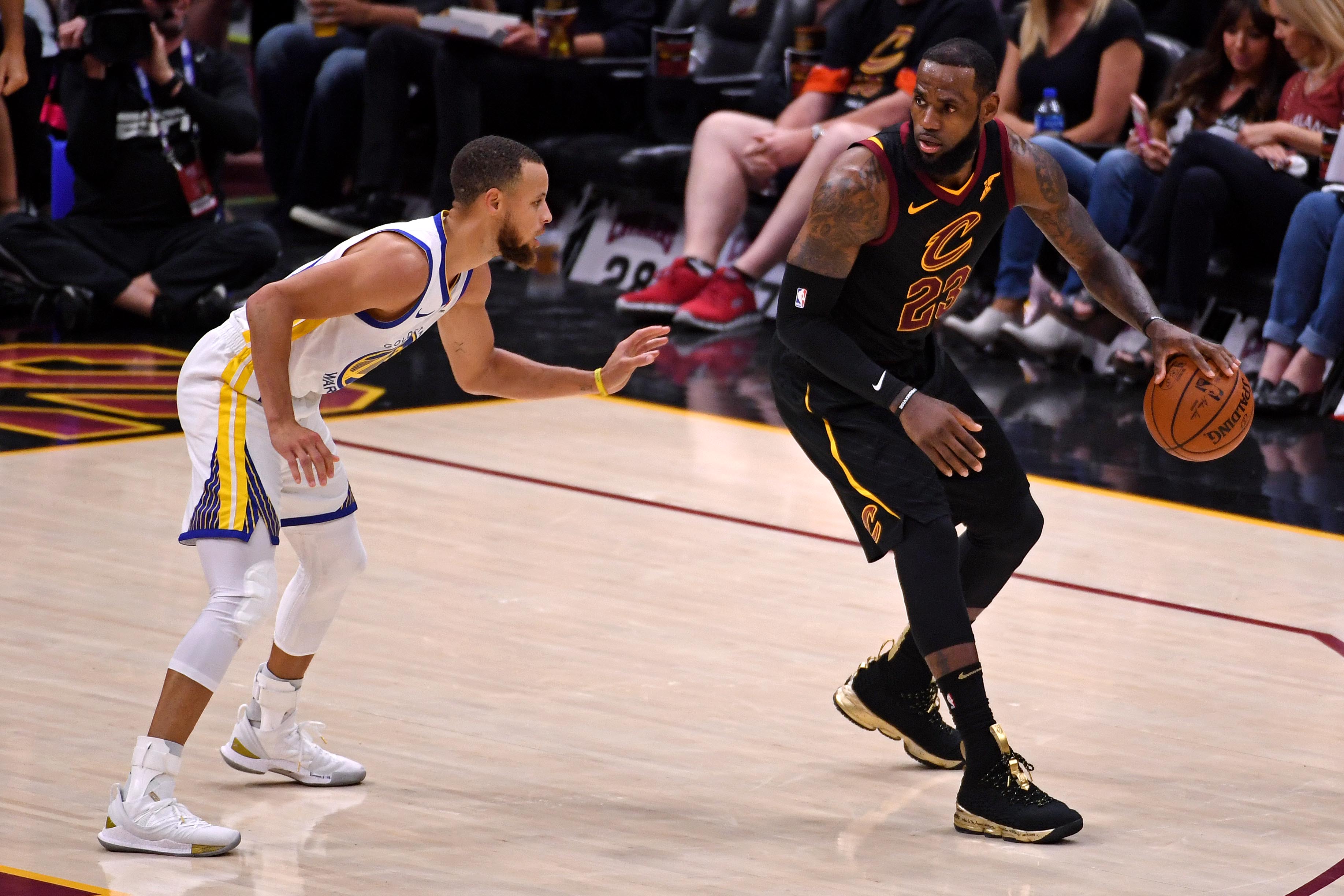 LeBron James dribbling the ball, guarded by Stephen Curry