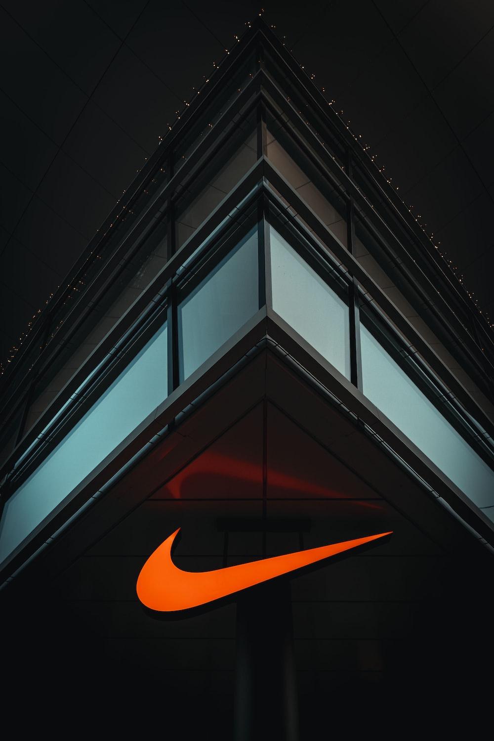 The Nike Logo Is Lit Up On Side Of A Building Photo