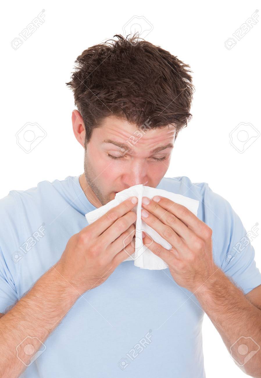 Young Man Sneezing In Tissue Isolated On White Background Stock