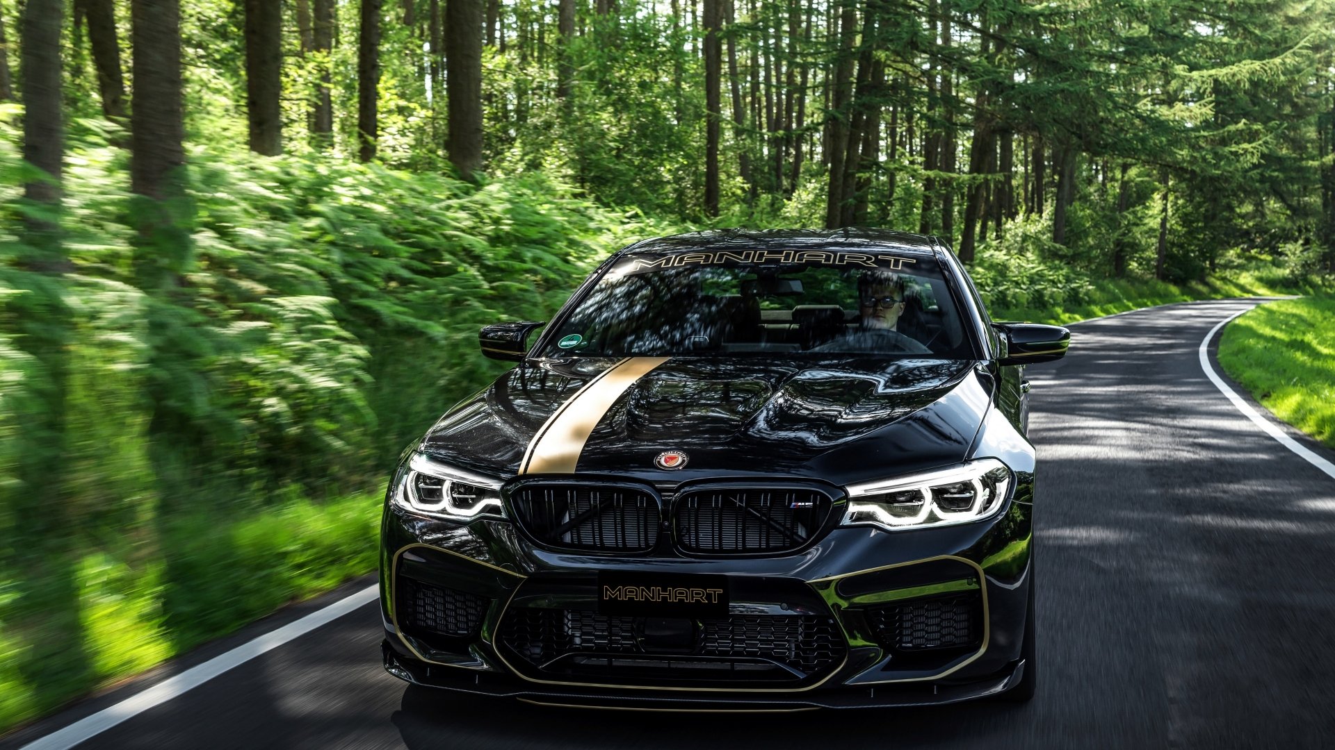Black BMW M5 Manhart MH5 800 driving on a forest road