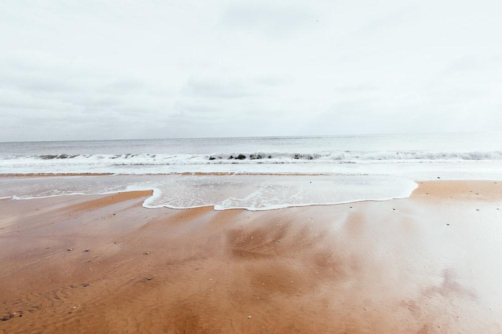Brown Sand Beach During Daytime Photo Water Image