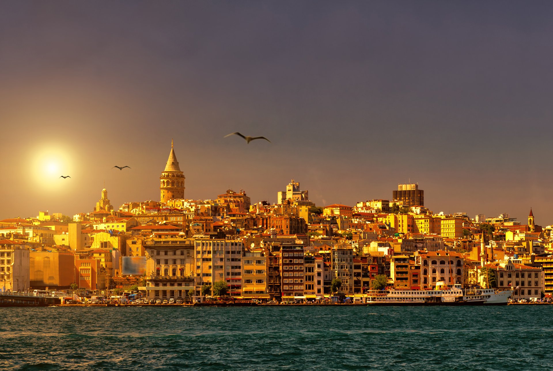 Golden sunset over the Galata Tower and Istanbul skyline, with seagulls soaring in the warm evening light
