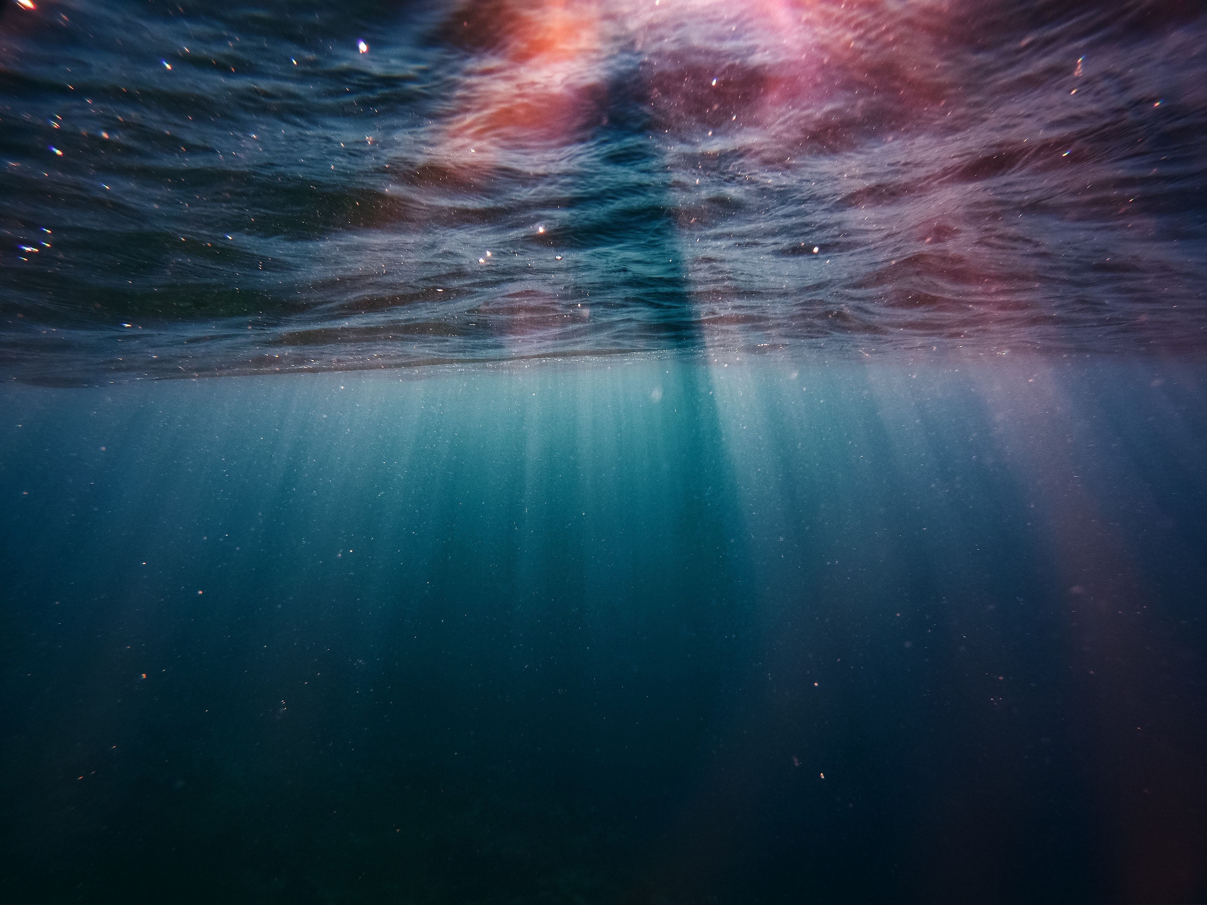 Sunlight piercing through the surface of a deep blue ocean, creating a mesmerizing underwater scene