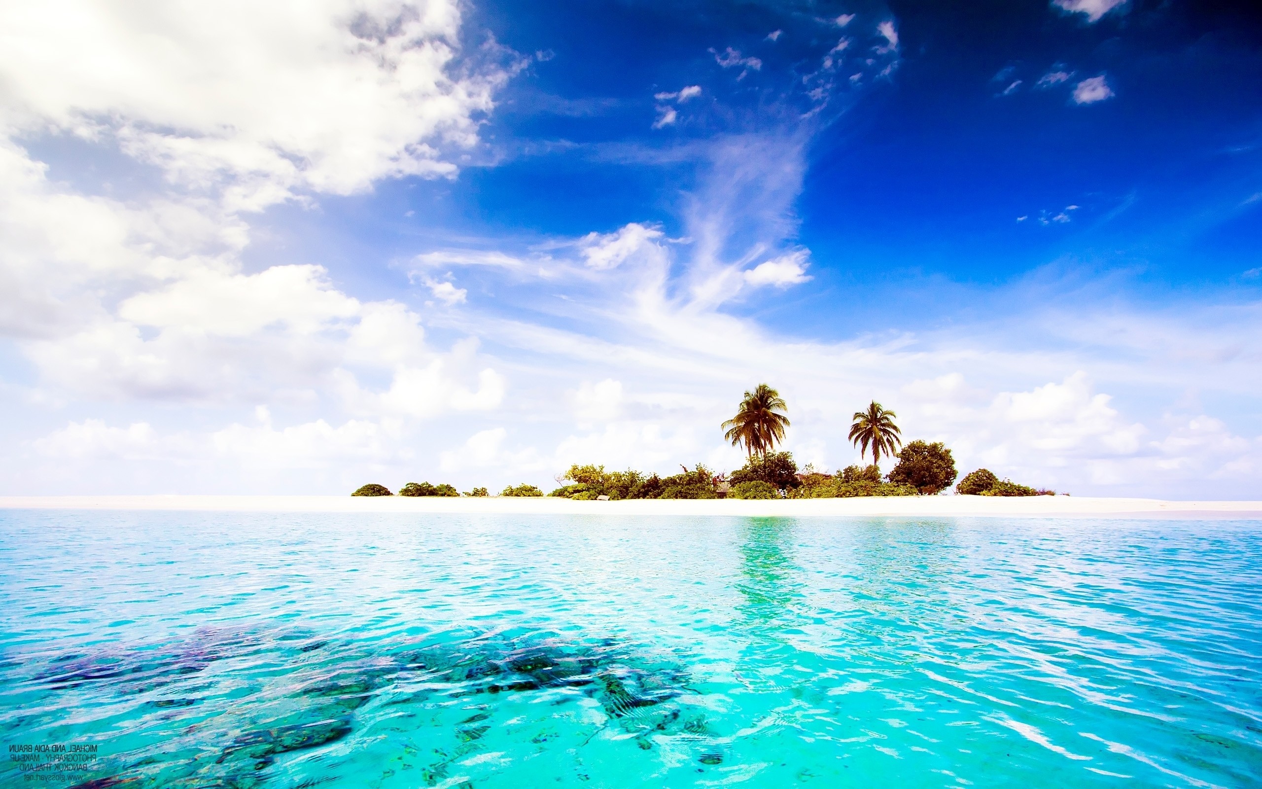 A picturesque tropical island with white sand beaches, turquoise water, and palm trees under a bright blue sky