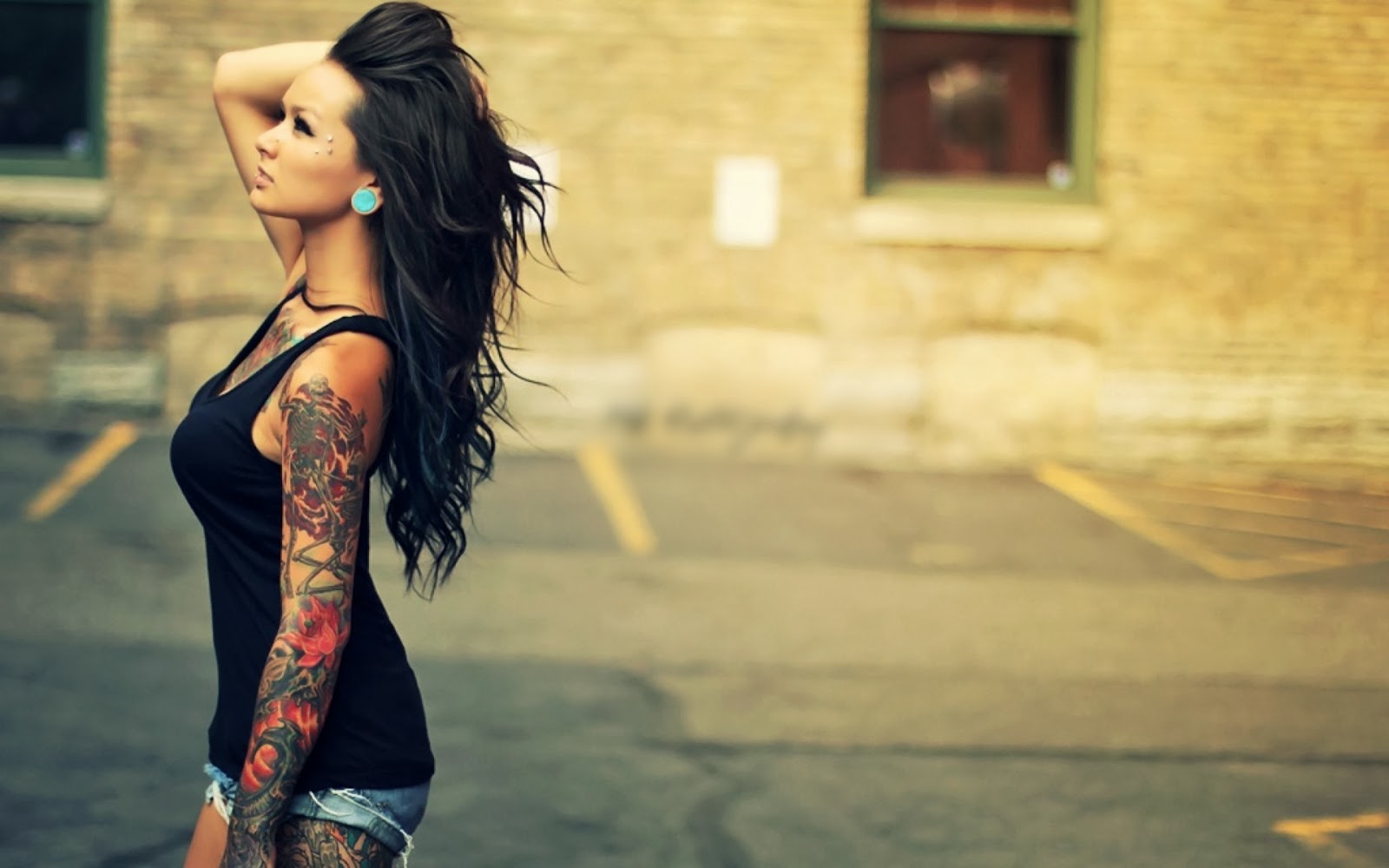 Woman with intricate floral sleeve tattoo and stretched earlobe piercing