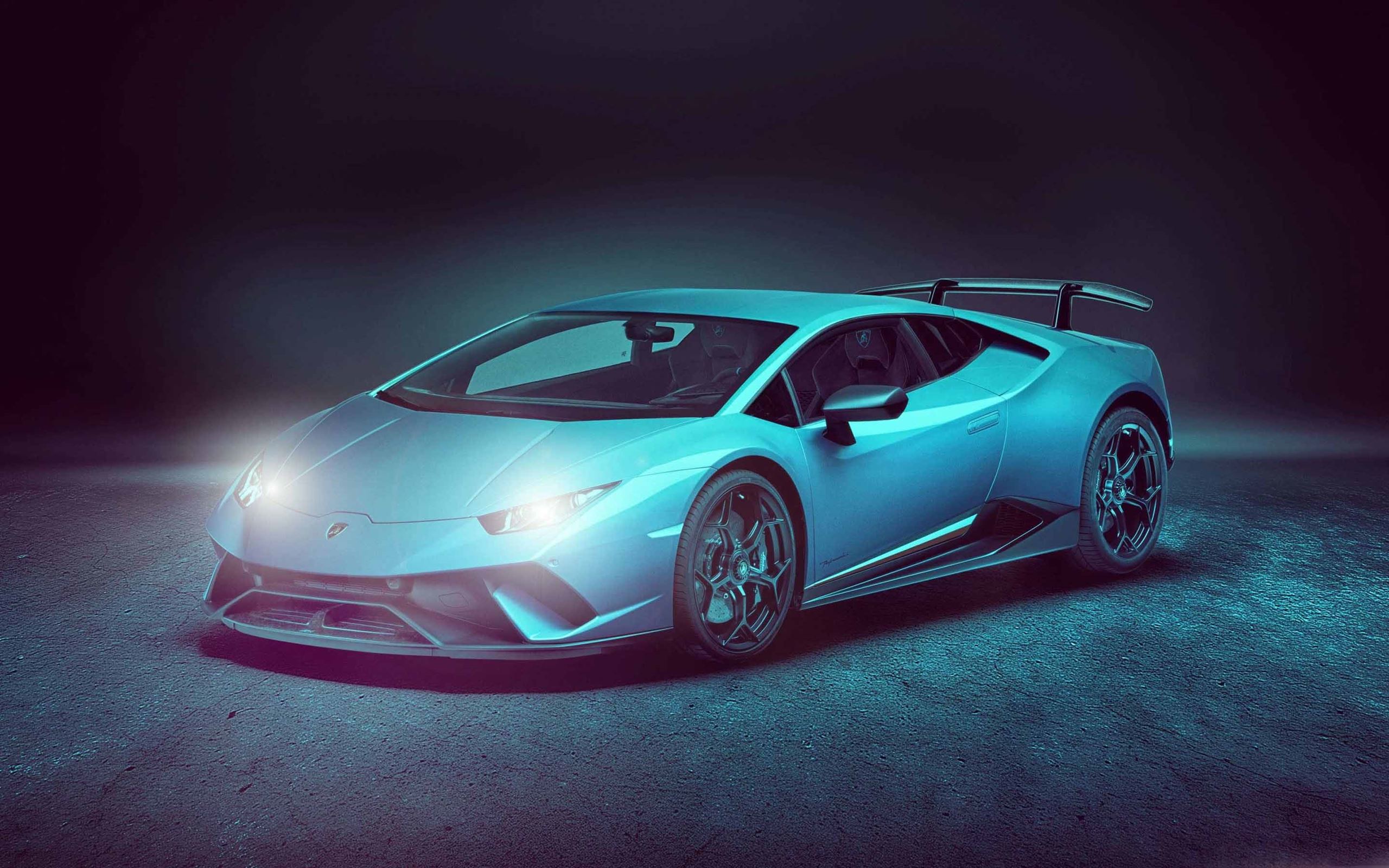A vibrant, light blue Lamborghini sports car, likely the Huracán Performante or Evo model, parked on a dark, textured surface under dramatic lighting