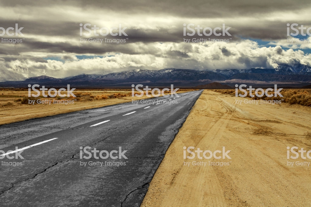 Long Mojave Desert Empty Road With Clouds And Mountains In The