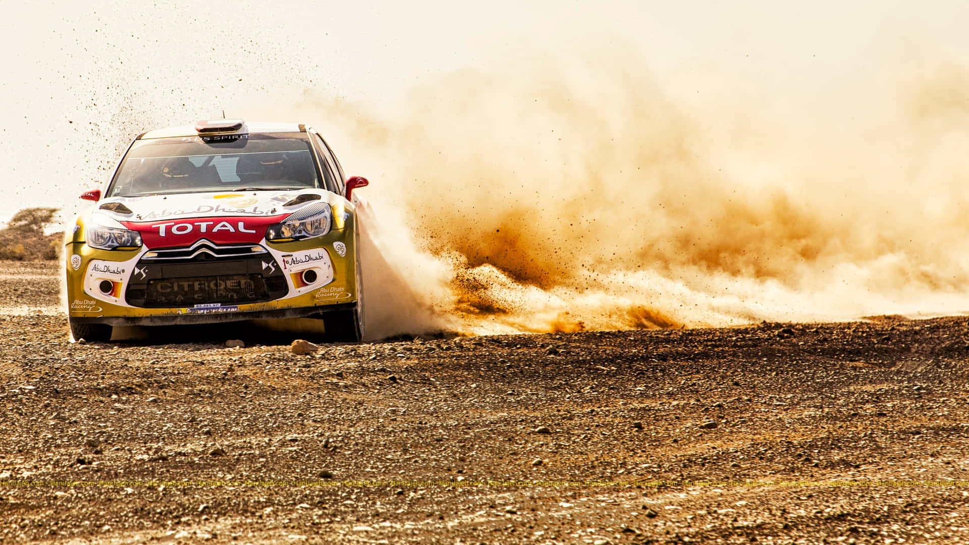 A Rally Car Driving Through Dusty Area Wallpaper